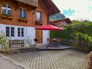 eine Terrasse mit einem Tisch und einem roten Regenschirm in der Unterkunft Chalet Hüsli by Interhome in Brienzwiler