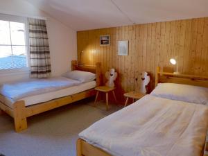 1 dormitorio con 2 camas, 2 sillas y ventana en Apartment Oltschiblick by Interhome, en Brienzwiler