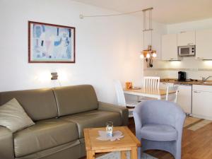 ein Wohnzimmer mit einem Sofa und einem Tisch sowie eine Küche in der Unterkunft Apartment Ostsee-Residenz - DMP173 by Interhome in Damp