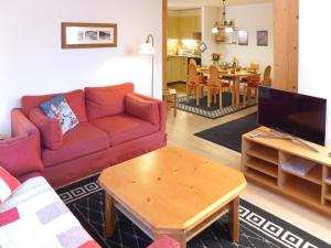 a living room with a red couch and a table at Apartment Terrasse Des Alpes 917 by Interhome in Crans-Montana +38 photos