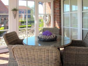 a table with chairs and a bowl of purple flowers on it at Apartment Rosenboom by Interhome in Wiarden