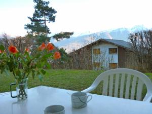 ein weißer Tisch mit einer Vase Blumen drauf in der Unterkunft Apartment Châtillon C 16 by Interhome in Ovronnaz