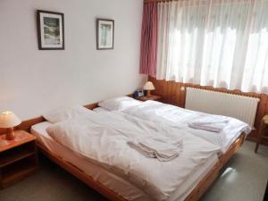 Schlafzimmer mit einem Bett mit weißer Bettwäsche und einem Fenster in der Unterkunft Apartment Châtillon C 16 by Interhome in Ovronnaz