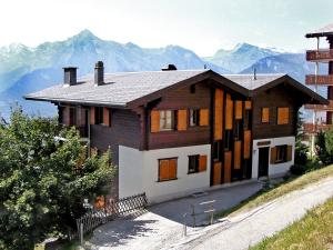 a house on a hill with mountains in the background at Apartment Les Bouillets by Interhome in Veysonnaz