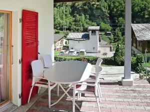 a table and chairs on a patio with a red door at Apartment Christl by Interhome in Embd