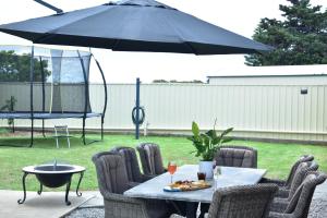 a table with chairs and an umbrella on a patio at Stan Breeze: Elegant Family Retreat in Stansbury