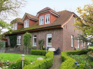 a red brick house with a garden in front of it at Apartment Alte Molkerei-1 by Interhome in Friederikensiel
