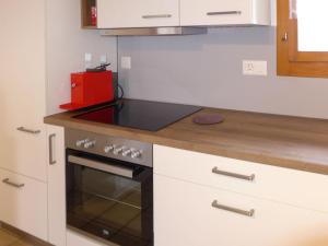 uma cozinha com armários brancos e um forno com placa de fogão em Chalet Hügli by Interhome em Bure mais 26 fotografias