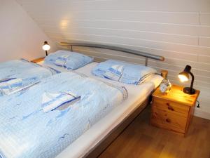 1 Schlafzimmer mit 2 Betten mit blauer Bettwäsche und einem Nachttisch in der Unterkunft Holiday Home Osterkamp by Interhome in Friederikensiel