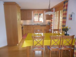 eine Küche mit gelbem Tisch und Stühlen in der Unterkunft Apartment Chalet Nagano by Interhome in Grindelwald