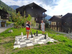 deux enfants jouant aux échecs sur un échiquier dans une cour dans l'établissement Apartment Aragon T100 by Interhome, à Fiesch