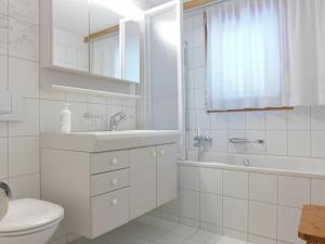 a white bathroom with a sink and a tub and a toilet at Apartment Rose Apt- Y by Interhome in Wengen