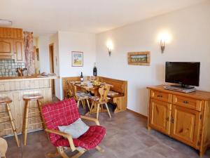 eine Küche und ein Esszimmer mit einem Tisch und einem TV in der Unterkunft Apartment Sapin Bleu 5 by Interhome in Villars-sur-Ollon