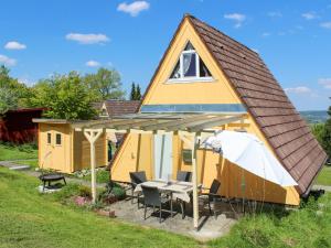 WilhelmsdorfにあるHoliday Home Ferienhäusle Nina by Interhomeの小さな黄色の家(テーブルと椅子付)