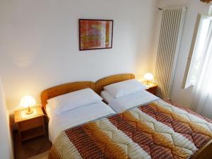 1 dormitorio con 1 cama con 2 almohadas y 2 lámparas en Apartment al Ronchetto by Interhome en Carona