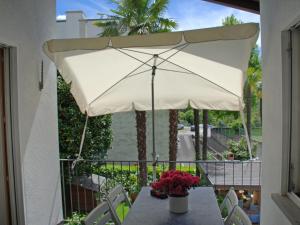 Apartment Casa tre G - App OG by Interhome في لوزون: طاولة مع مظلة بيضاء على شرفة