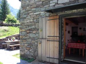 ein Steingebäude mit einer Holztür und einem Tisch in der Unterkunft Holiday Home Dara Cotta by Interhome in Alpe di Scieru