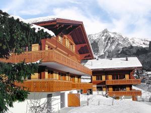 a large wooden building with a snow covered mountain at Apartment Chalet Eiger-2 by Interhome in Grindelwald