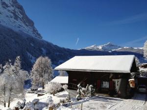 un edificio coperto di neve con le montagne sullo sfondo di Apartment Chalet Bärgsunna-4 by Interhome a Grindelwald