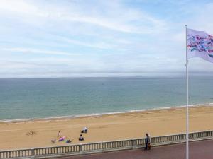 a beach with a flag and people sitting on the beach at Apartment Isabelle-1 by Interhome in Cabourg