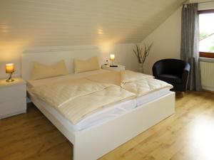 a white bed in a bedroom with a black chair at Apartment Land in Sicht by Interhome in Rulfingen
