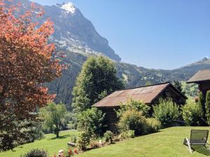 uma casa num campo com uma montanha ao fundo em Apartment Chalet Bärgsunna-2 by Interhome em Grindelwald
