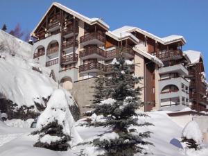 un edificio cubierto de nieve con un árbol de Navidad delante de él en Apartment La Grande Chaume by Interhome, en Les Deux Alpes