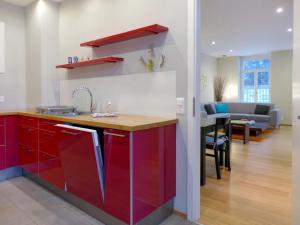 شقة سافوي إليغانس في إنترلاكن: مطبخ مع دواليب حمراء وغرفة معيشة