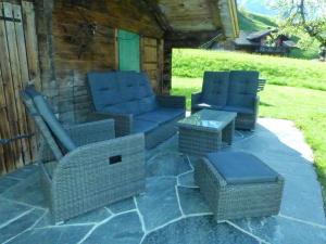 4 sillas de mimbre y mesas en un patio de piedra en Apartment Chalet Schwendihus-6 by Interhome, en Grindelwald