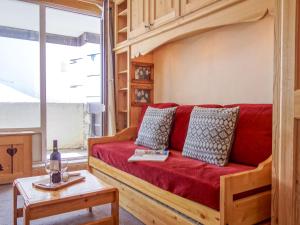 um sofá vermelho num quarto com uma grande janela em Apartment Le Pramecou-5 by Interhome em Tignes