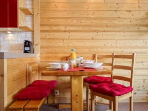 uma mesa de madeira com cadeiras almofadadas vermelhas à volta em Apartment Le Pramecou-5 by Interhome em Tignes