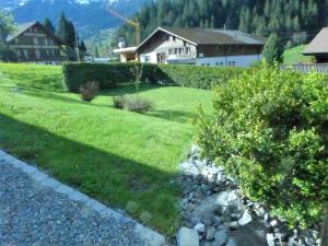 un giardino con prato e cespugli e una casa di Apartment Chalet Schwendihus-11 by Interhome a Grindelwald