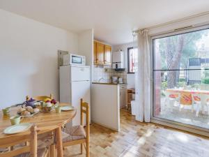 cocina y comedor con mesa y nevera en Apartment Le Centaure by Interhome, en Cap d'Agde