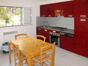 a kitchen with a wooden table and red cabinets at Apartment L'Aghja Nova - GAL106 by Interhome in Galeria