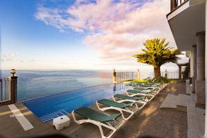 einen Pool mit Liegestühlen und Meerblick in der Unterkunft Ocean Cliff in Ponta do Sol