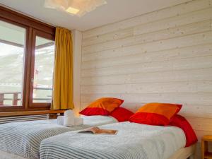een slaapkamer met 2 bedden met rode en oranje kussens bij Apartment Le Curling B - Val Claret-27 by Interhome in Tignes