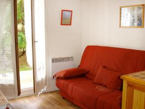 un divano rosso in un soggiorno con finestra di Apartment Sapin B by Interhome a Demi-Quartier