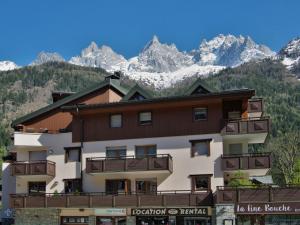 un grand bâtiment avec des montagnes en arrière-plan dans l'établissement Apartment L'Espace Montagne-8 by Interhome, à Chamonix-Mont-Blanc