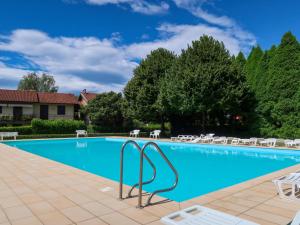 una grande piscina con sedie e alberi di Apartment Red Sunset by Interhome a  Monvalle 