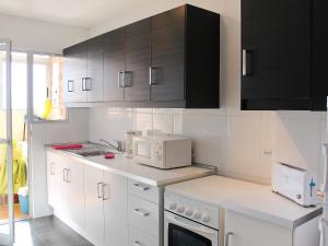uma cozinha com electrodomésticos brancos e armários pretos em Apartment Las Cinco Torres by Interhome em El Campello