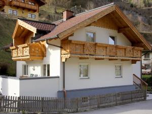 a house with wooden balconies and a fence at Apartment Haus Toferer by Interhome in Grossarl