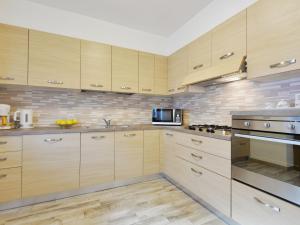 uma cozinha com armários de madeira e electrodomésticos de aço inoxidável em Apartment Bernard-1 by Interhome em Campestrin
