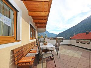 a balcony with a table and chairs and a view of mountains at Apartment Christian by Interhome in Pettneu am Arlberg