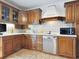 a kitchen with wooden cabinets and a white dishwasher at Apartment Florian Pia by Interhome in Pozza di Fassa