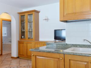 a kitchen with wooden cabinets and a sink and a tv at Apartment Ardoney-1 by Interhome in Campitello
