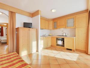 a kitchen with wooden cabinets and a tiled floor at Apartment Lazzer-1 by Interhome in Campitello