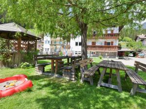 un parco con tavoli da picnic, un albero e una barca di Apartment Cecilia-3 by Interhome a Campitello