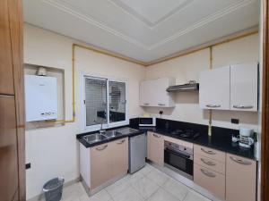 a kitchen with white cabinets and a sink at Appartement Elyssa in Tunis