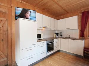 a kitchen with white cabinets and a tv on the wall at Holiday Home Schwendau-2 by Interhome in Hippach +41 photos