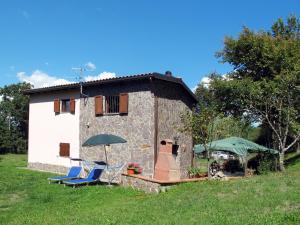 Casa de piedra pequeña con 2 sillas y sombrilla en Holiday Home Grande Quercia by Interhome en Pallerone
